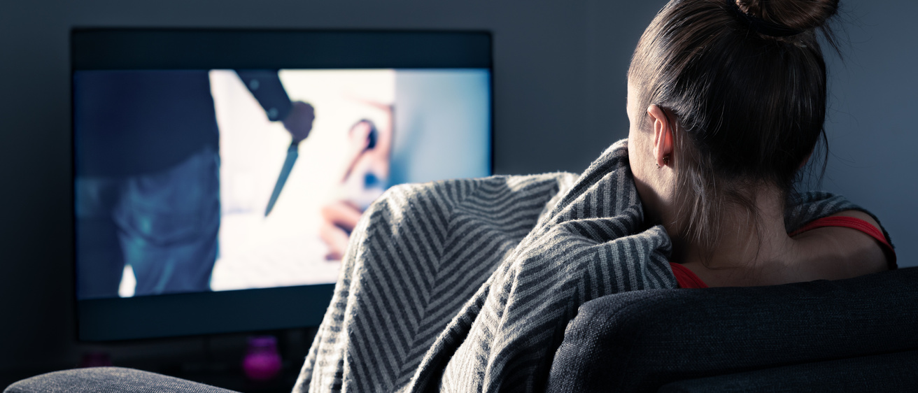 Woman staring at TV, afraid